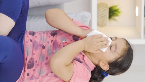 Vertical-video-of-Girl-child-covering-his-mouth-and-nose-with-a-tissue-while-coughing.